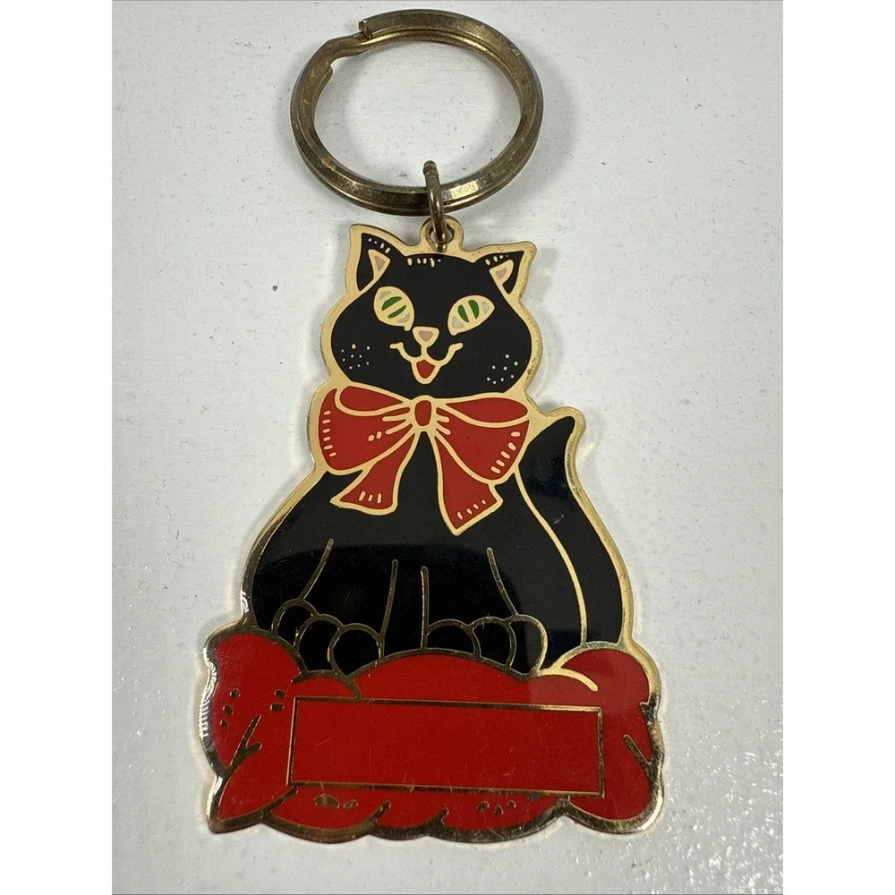 Black cat enamel keychain with gold-toned metal accents and‎ a red bow